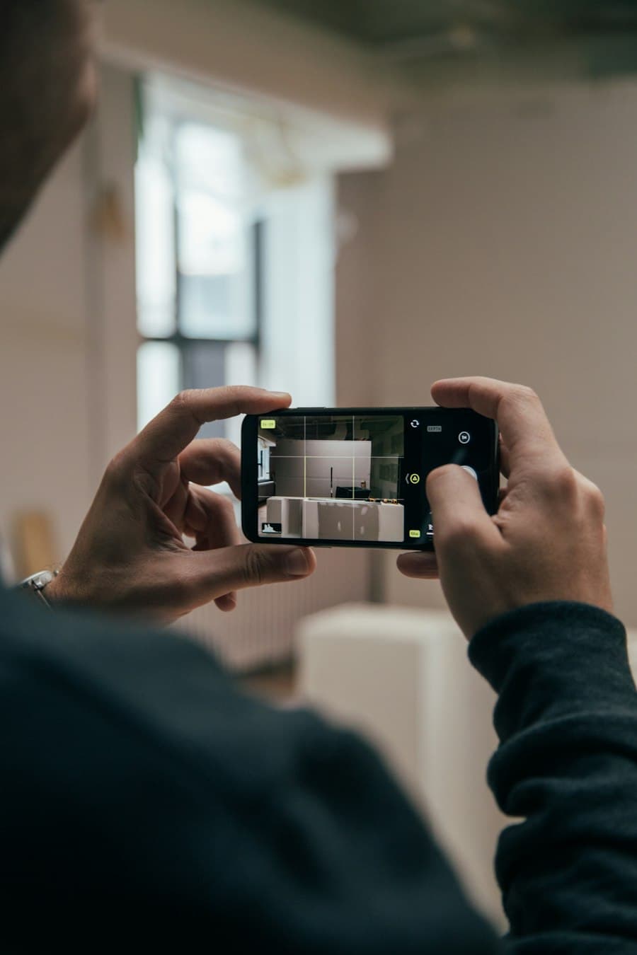 Deux mains cadrent une pièce lumineuse avec l'appareil photo d'un téléphone